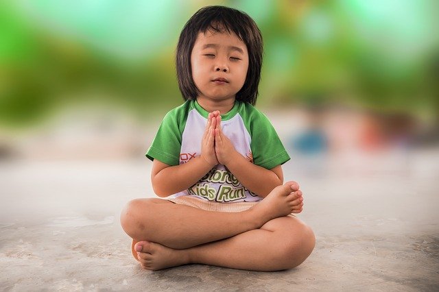 asiatisches Kind meditierend im Lotussitz
